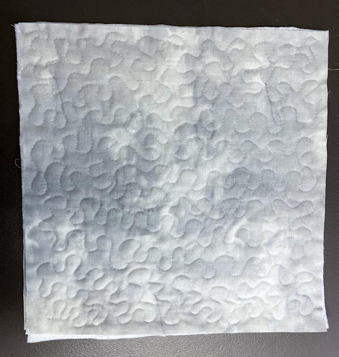 Free motion quilted stipples on a white piece of fabric; Fabric Creations Textured Grey