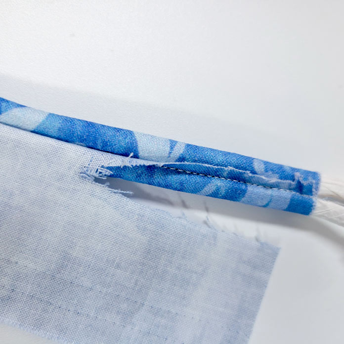 A tube of blue fabric with the excess at one end partially trimmed