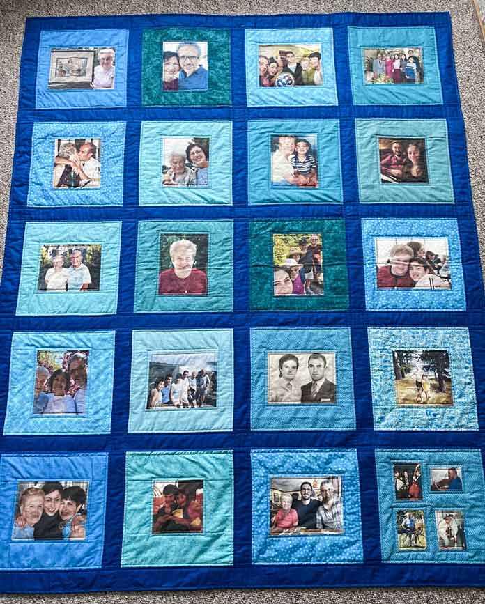The completed memory quilt with family photos framed in a variety of light blue fabrics and dark blue strips.