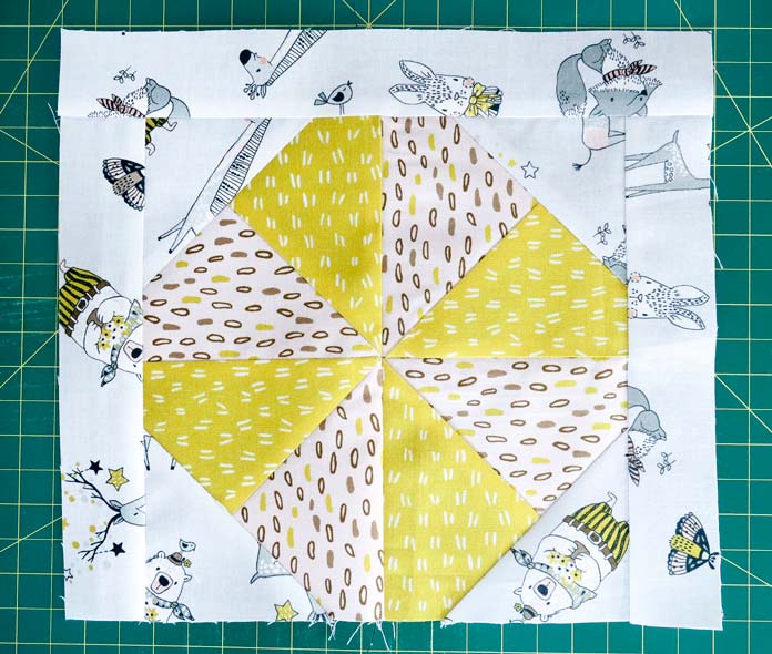 Fabric strips are sewn onto three sides of each pinwheel block. Whimsicals collection by Michael Miller Fabrics, Oliso M2Pro Mini Project Iron, UNIQUE quilting Wool Pressing Mat, Gütermann Cotton 50 wt. Thread, Gütermann 26-piece 100% Cotton 100m Thread Set with Storage Box, Klassé Sharps Needles - Size 80/12, Klassé Sharps Needles - Assorted Sizes 60/8, 70/10, 80/12