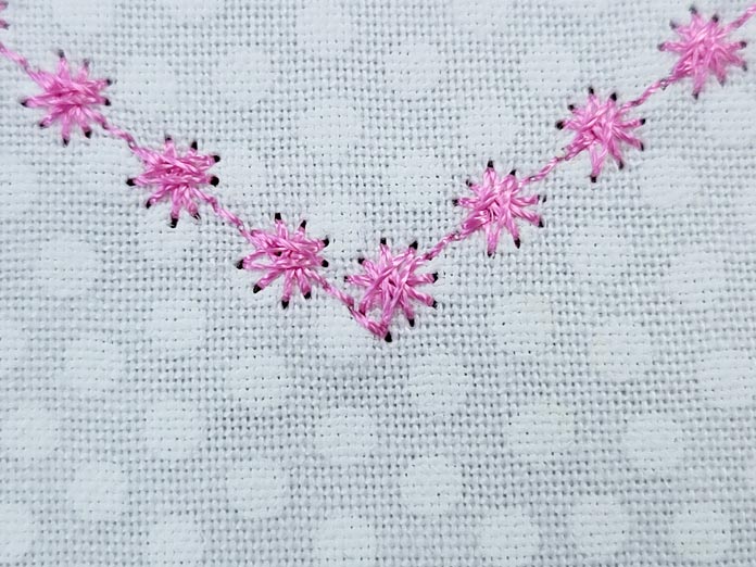 Pink candle-wicking stitches on white fabric