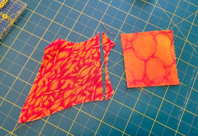 Two pieces of orange fabric on a green cutting mat