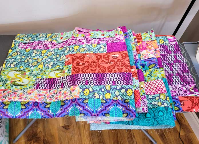 Eight strips of multi-colored fabric on an ironing board