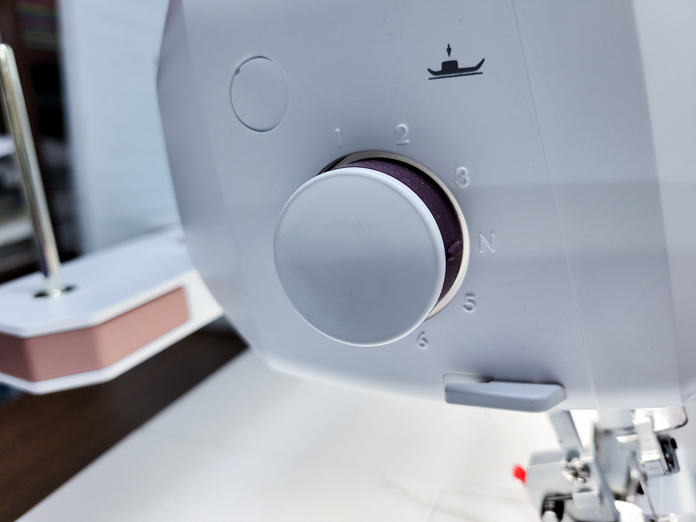 A white handle on the side of a serger; Husqvarna Viking Amber Air S600