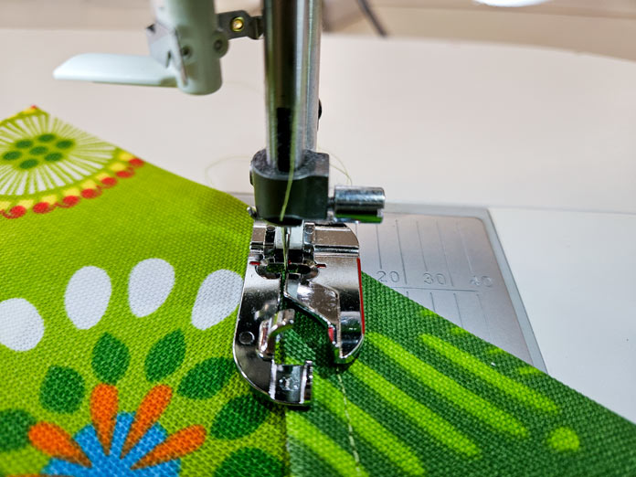 A metal presser foot on green fabric; Gütermann Nostalgia Box - 50wt Cotton Thread 100m - 48 Shades, Gütermann Nostalgia Box, Flat Felled Foot 9mm, Husqvarna VIKING Opal 690Q, free sewing pattern, outdoor accessories, outdoor cushions
