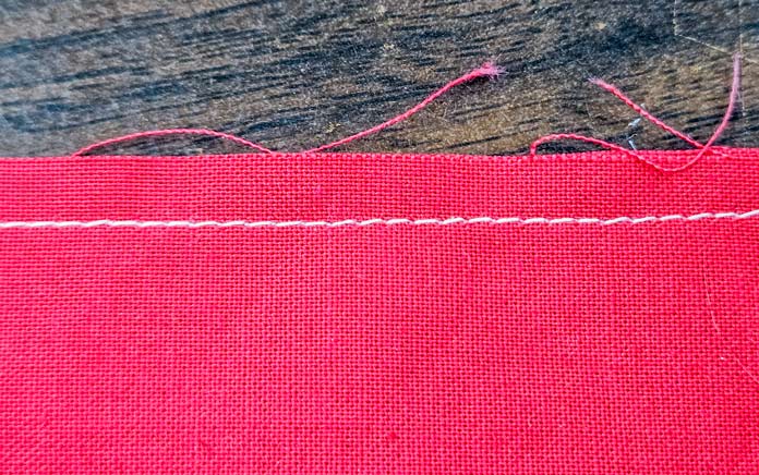 White stitches on red fabric; Husqvarna VIKING Designer Quartz 29, mySewnet Machine Embroidery Software, Husqvarna VIKING Tear-a-Way Light Stabilizer 15 Inches x 25 Yards