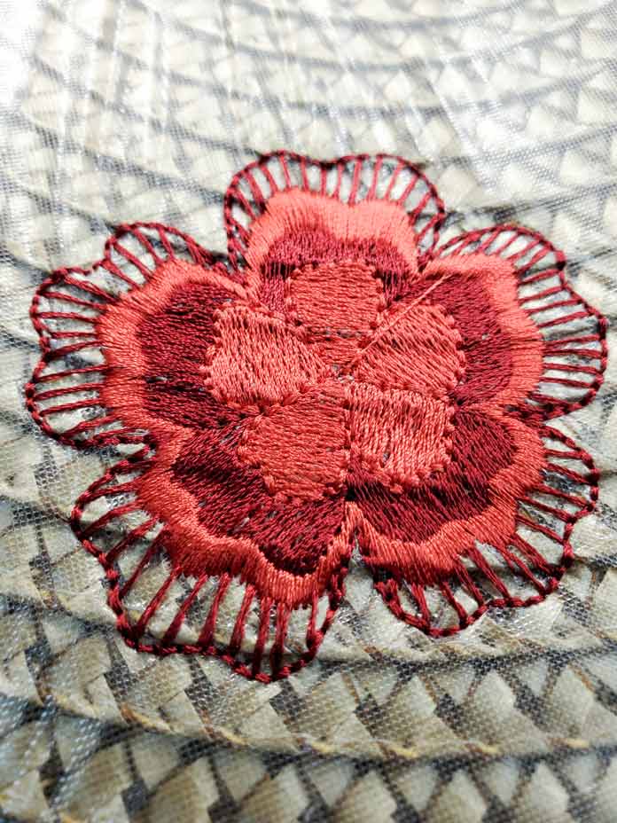 A floral motif in two shades of red on a synthetic rattan table topper