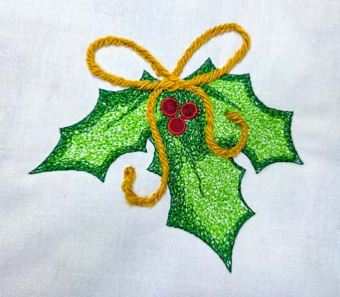 A machine-embroidered holly leaf with a gold yarn bow