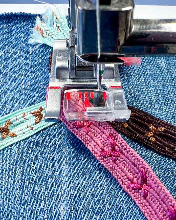 Close-up of the 2A Fancy Stitch Foot on the PFAFF Creative Icon 2 sewing machine during the triple ribbon stitch process. The machine has completed the initial short section of stitching and paused automatically, as part of the programmed sequence. 