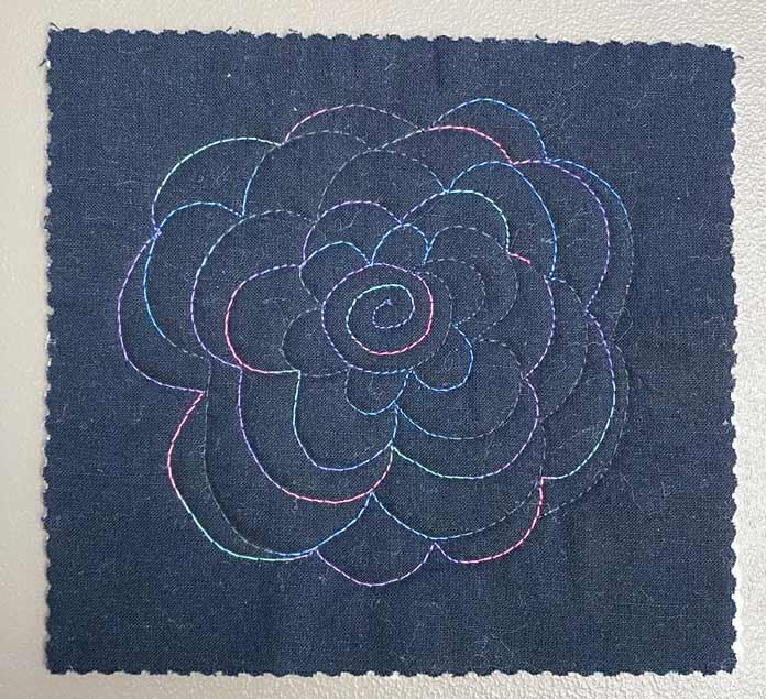 Cabbage rose free motion quilting design on black fabric; Gütermann Variegated Thread