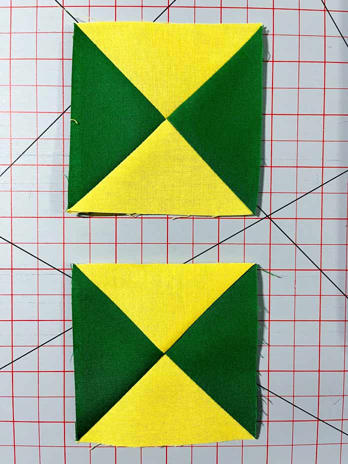 Two completed yellow and green fabric Quarter Square Triangles. Clover Thread Cutter Pendant, Clover Chaco Liner, Clover Quilting Pins