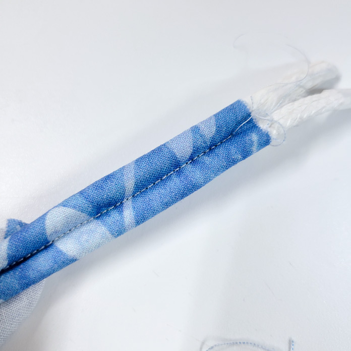Two lengths of white cord encased in a tube of blue fabric with a line of blue stitching in the center