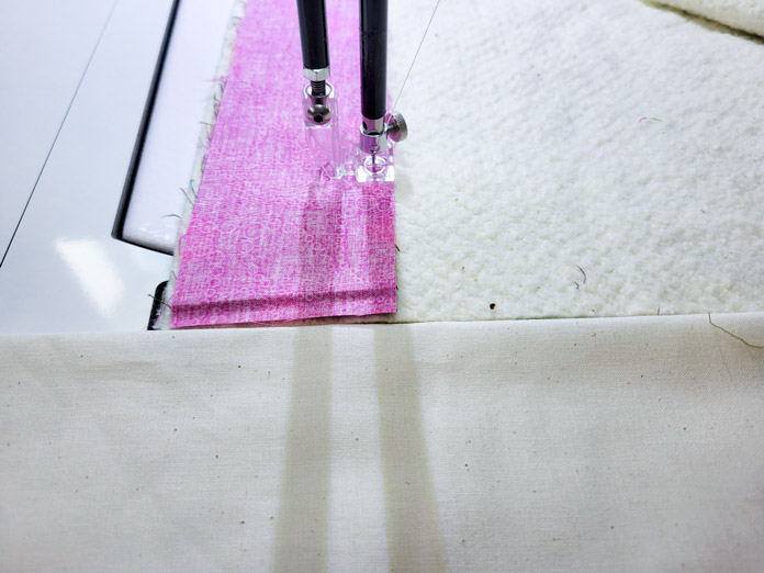 Pink fabric, batting, and muslin under the needle of a stationary quilting machine; Husqvarna Viking PLATINUM™ Q160, Husqvarna Viking Square Feet Set