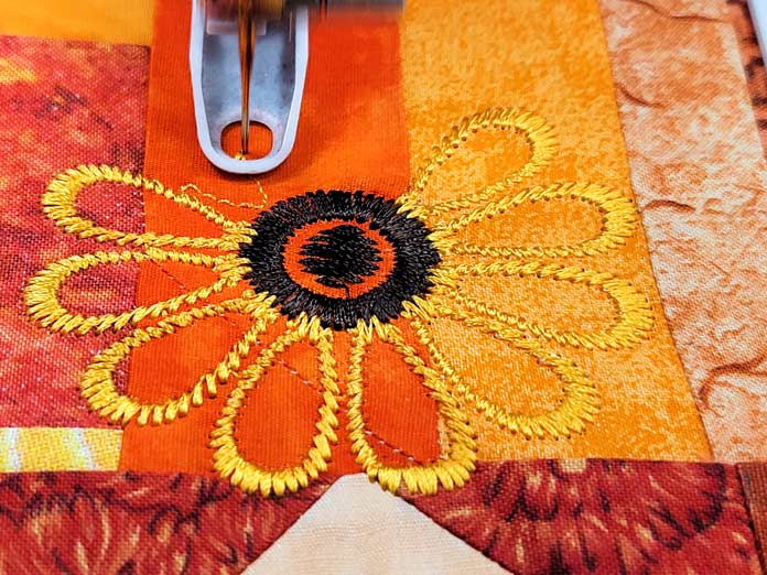 A machine embroidery flower on orange fabric; Husqvarna Viking DESIGNER EPIC 2