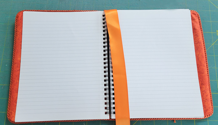 The inside of a spiral-bound journal with an orange ribbon bookmark
