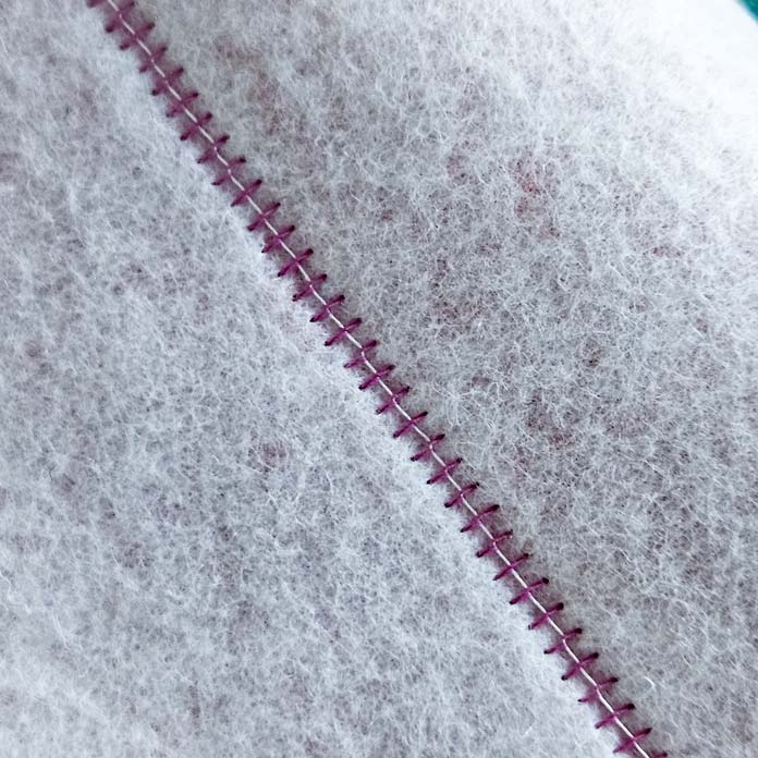A row of pink and white stitching on white fabric; quilting a project bag using Gütermann Thread, a twin needle, and the Husqvarna VIKING ONYX 25