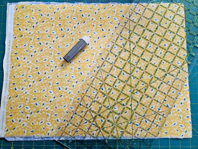 Yellow fabric with a quilter's ruler and white chalk tool