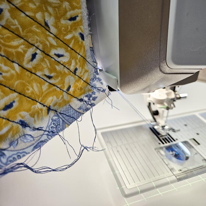 Yellow fabric with blue stitching beside a sewing machine; Thread Cutter on the Husqvarna VIKING DESIGNER EPIC 3