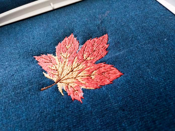Embroidered red and gold maple leaf on navy fabric. Brother Luminaire XP