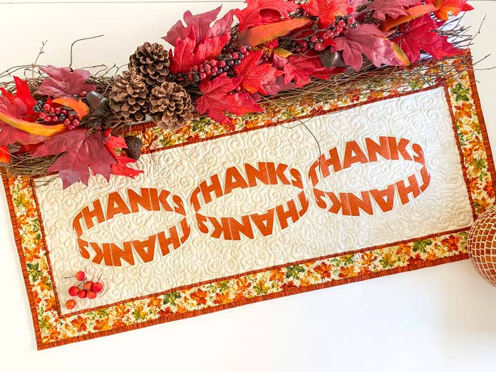 A beige table runner with machine embroidery fonts as the design; quilting, embroidery machine, machine embroidery, quilting techniques, Husqvarna VIKING, quilt labels, embroidery software, quilt embellishments, quilting tools, QUILTsocial