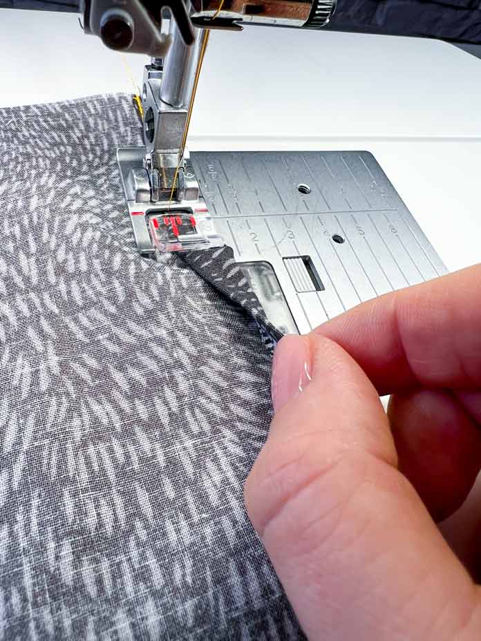 Close-up of hand folding the hem and stitching with a PFAFF 2A Fancy Stitch Foot for IDT System