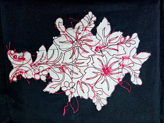 Red stitching on black fabric with white paper