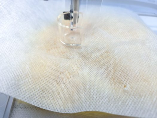 A felting needle on white fabric