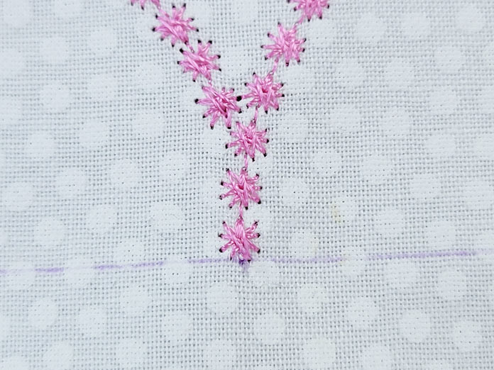 A V-shape of pink candle-wicking stitches