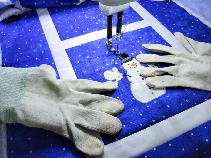 A pair of quilting gloves on blue and white fabric; PFAFF powerquilter 1600