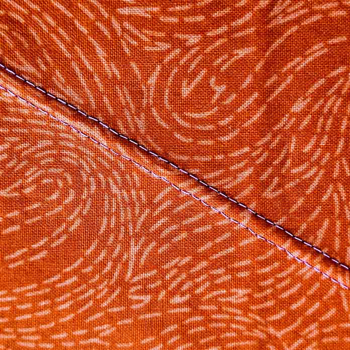 Two lines of pink stitching on orange fabric; quilting a project bag using Gütermann Thread, a twin needle, and the Husqvarna VIKING ONYX 25