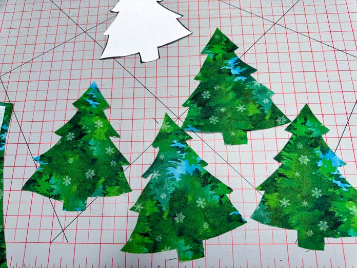 Four Christmas tree shapes cut out of green fabric.