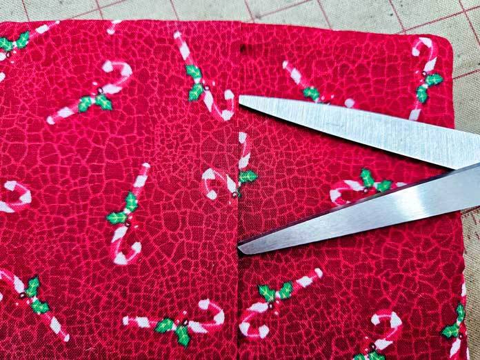 Red fabric with candy canes and the blades of a pair of scissors; HeatnBond Lite, quilt binding, fusible web, fabric crafts