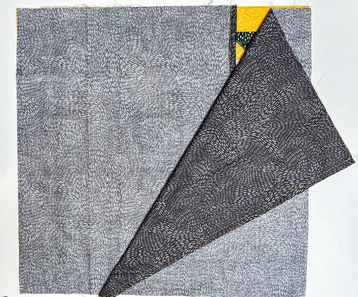 Layer of the two backing pieces on top with right sides facing down, overlapping the folded edges on the table