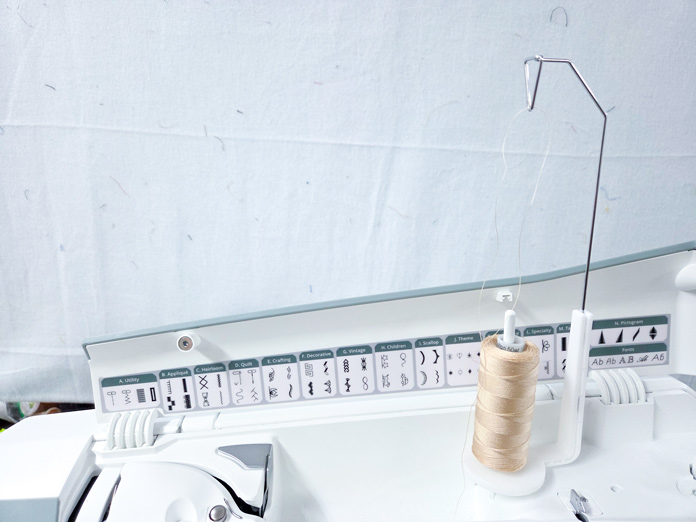 A spool of thread in a vertical position on a sewing machine