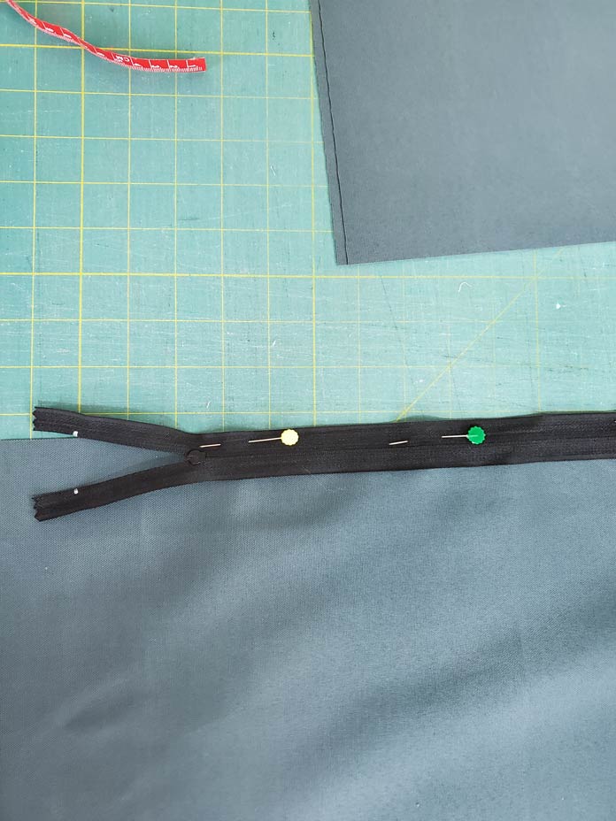 A black zipper pinned to a piece of green fabric. Husqvarna Viking Designer Sapphire 85, Inspira EZ Snip Curved Scissors