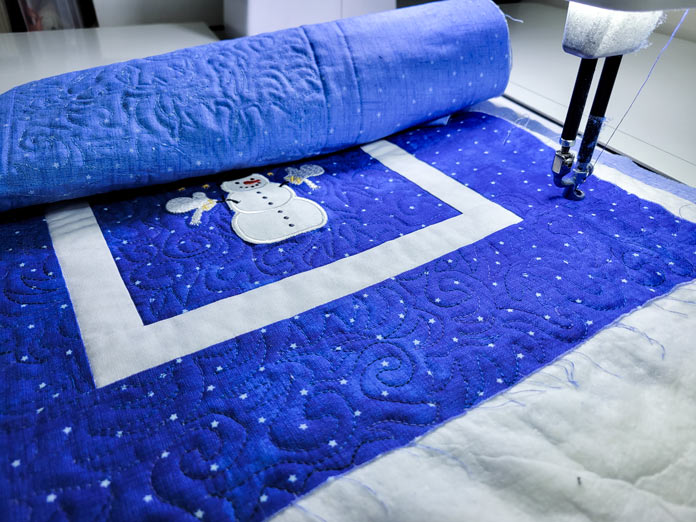 A blue and white table runner under the needle of a quilting machine; PFAFF powerquilter 1600