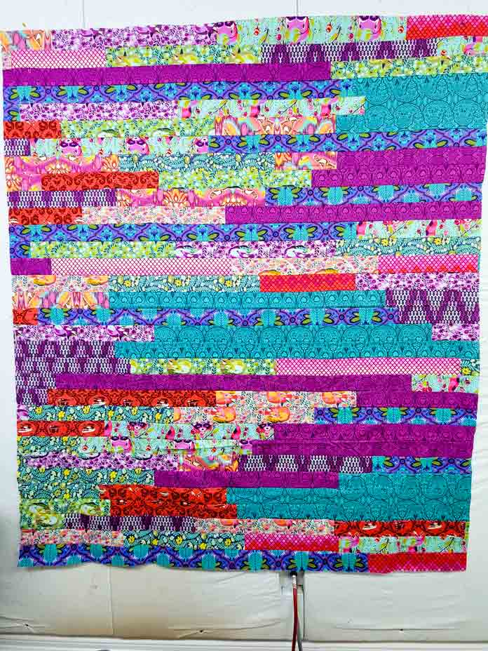 A multi-colored quilt on a white wall