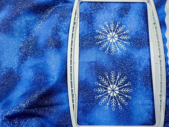 2 white embroidered snowflakes on blue fabric; Husqvarna VIKING Designer Quartz 29, mySewnet Machine Embroidery Software, mySewnet Library, Husqvarna VIKING Tear-a-Way Light Stabilizer 15 Inches x 25 Yards