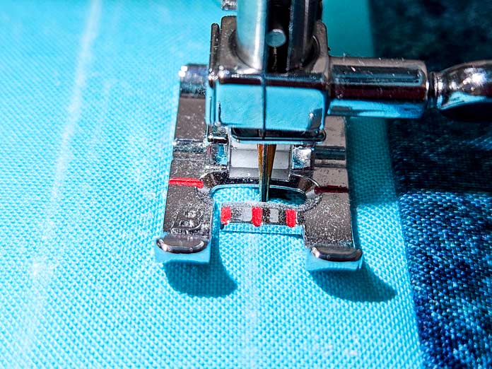 A metal presser foot on a sewing machine