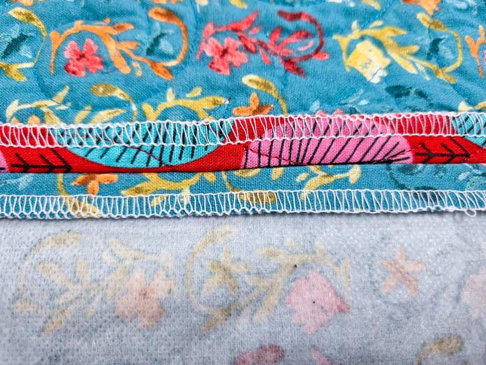 Blue fabric with a serged edge in white thread