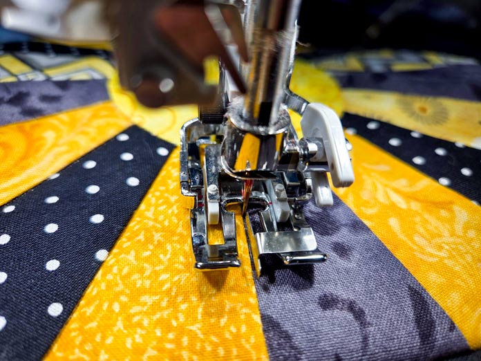 A metal presser foot on yellow and black fabric