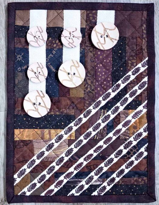 A brown and beige quiltlet with buttons and decorative threads
