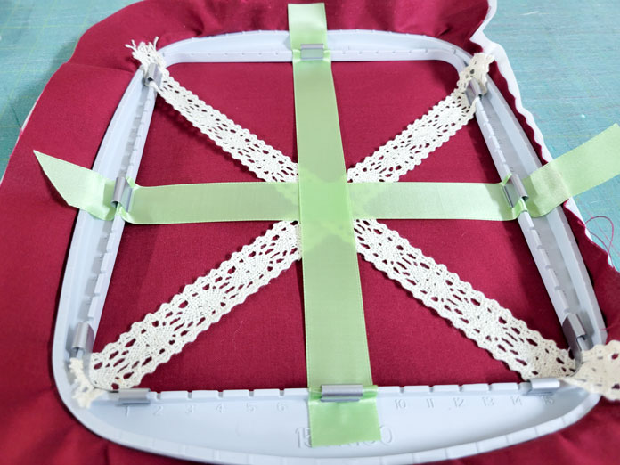 Green ribbon and cream lace on burgundy fabric in a machine embroidery hoop; Husqvarna Viking Texture Hoop