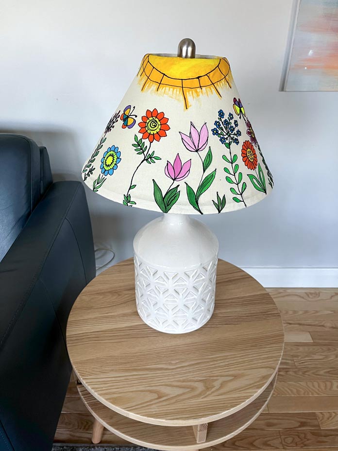 Picture of a lamp on a round top side table with a painted and stitched floral lampshade on a neutral background fabric; Mont Marte Signature Fabric Paint Set, Gütermann Thread