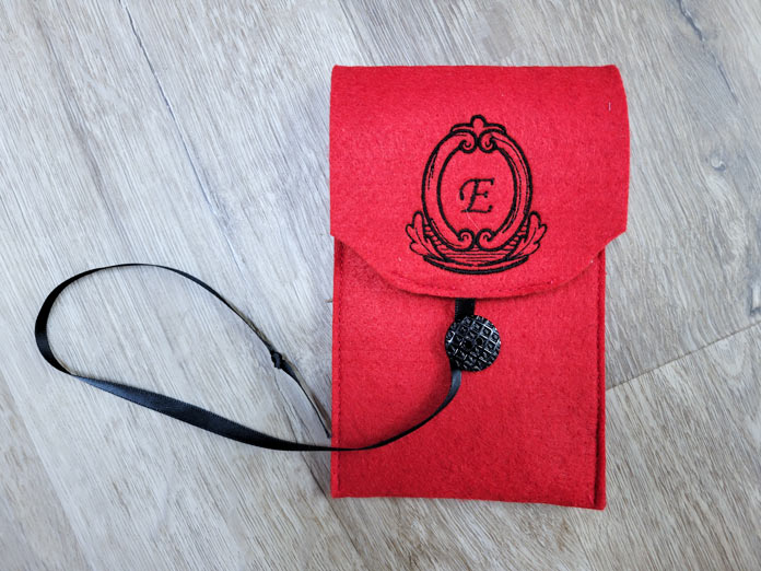 A red felt phone case with the initial E in black stitching