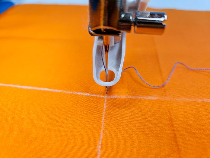 An orange quilt square and a plastic presser foot; Husqvarna VIKING DESIGNER EPIC 3