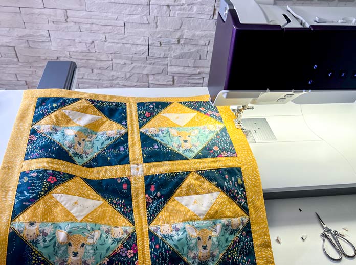 A purple model of the PFAFF creative icon 2 with attached embroidery unit and final stitching the cushion case