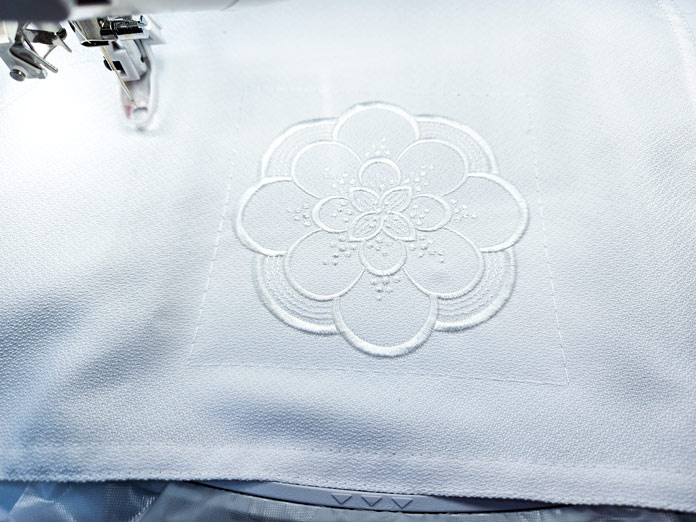 A white machine embroidery design on a white napkin