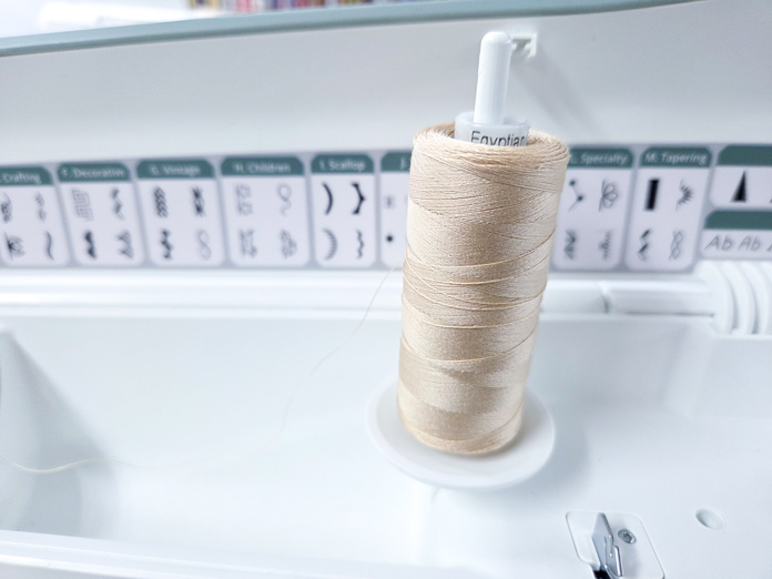 A spool of thread in a vertical position on a sewing machine