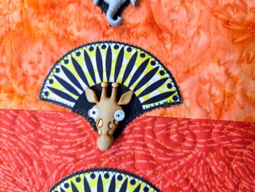 A giraffe button on orange fabric